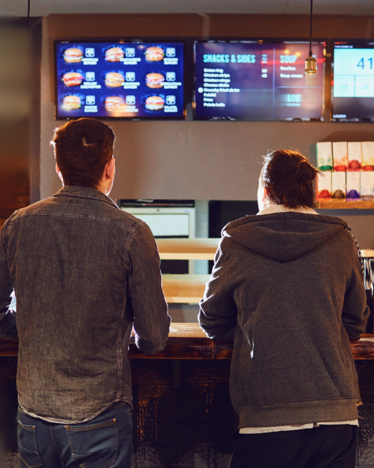 Two guys staring at a menue at a fast food restaurant.