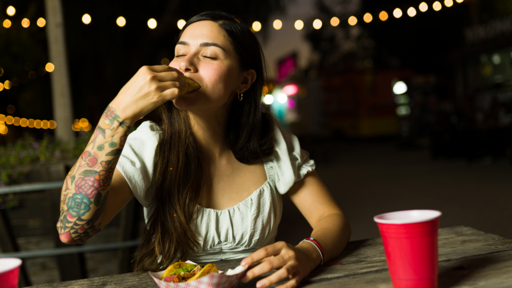 Women outside eating a taco with a red solo cup.